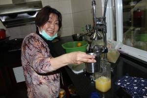 My aunt Dao-Liou proudly squeezing orange juice in her kitchen